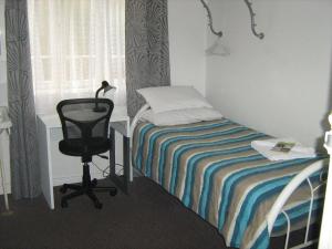 1 dormitorio con cama, escritorio y silla en Kookaburra Inn, en Brisbane