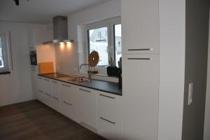 a kitchen with white cabinets and a sink and a window at Vakantiehuiswinterberg in Winterberg