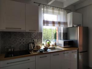 kuchnia z białymi szafkami, umywalką i oknem w obiekcie Kaszubska Przystań w mieście Brzeźno Szlacheckie