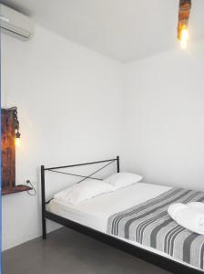 un letto con lenzuola e cuscini bianchi in una stanza di Prickly Pear House a Plaka Milou