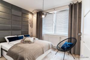 - une chambre avec un lit et une chaise dans l'établissement Apartament Blue II Koszalin, à Koszalin
