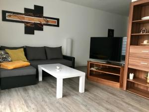 sala de estar con sofá, TV y mesa en Ferienwohnungen am Feldrain - Gornau im Erzgebirge en Zschopau