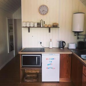 a kitchen with a microwave and a sign on a counter at Mo's Cottage in Kilmore