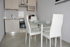 a kitchen with a glass table and white chairs at Apartman 2 in Senj