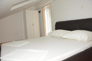 a white bed with a black headboard and white pillows at Apartman 2 in Senj