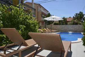 a pair of chairs and an umbrella next to a pool at Apartman 2 in Senj