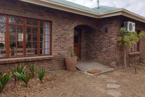 a brick house with a door and a patio at Coral Tree House in Graaff-Reinet
