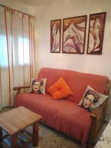 Casa Rural SIGLO XX في Calmarza: غرفة معيشة مع أريكة حمراء عليها صورتين