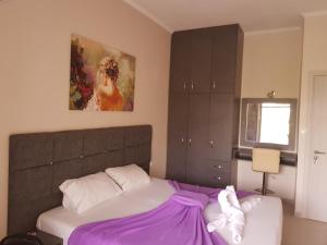 a bedroom with a bed with purple sheets and a painting at Venus Sea View Apartment in Perivólion