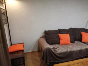 a couch in a room with orange pillows on it at Residence le Cairn in Le Monêtier-les-Bains