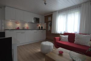 sala de estar con sofá rojo y cocina en Haus Wiedersehen, Weissmies (3-Zi), en Saas-Grund