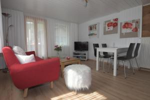 a living room with a red chair and a table at Haus Wiedersehen, Weissmies (3-Zi) in Saas-Grund