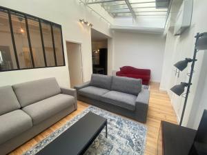 una sala de estar con 2 sofás y un sofá rojo. en Loft 3 chambres Bastille, Marais, Père Lachaise en París