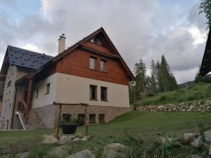 a house with a wooden roof on a field at Darmilus apartmány in Demanovska Dolina