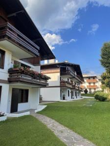 a white building with balconies and a green yard at Chez Tina in Asiago