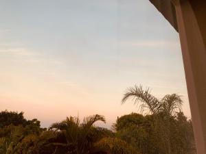 a view of the sunset from a house with palm trees at Tshamani self catering in Hazyview