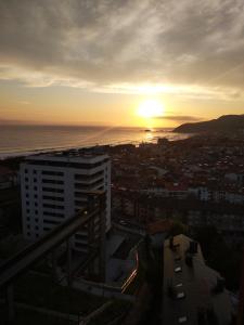 um pôr-do-sol sobre o oceano e uma cidade em SARAKATUA15 vistas espectaculares - familias y parejas - 2 dormitorios independientes - amplio salón cocina comedor - tarjeta parking OTA GRATIS zona azul y residentes - Estancia mínima 2 noches - julio y agosto de domingo a domingo 7 noches - em Zarautz