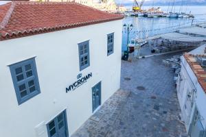 a white building next to a marina with boats at MyCrown Suite, Luxurious apartment with sea view located at the port of Hydra in Hydra