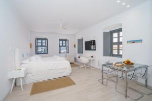 MyCrown Suite, Luxurious apartment with sea view located at the port of Hydra في هيدرا: غرفة نوم بيضاء مع سرير أبيض وطاولة