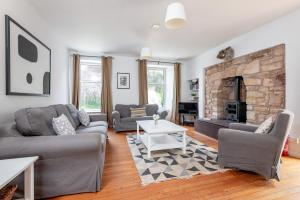 a living room with couches and a fireplace at Madeira In Fife in Pittenweem