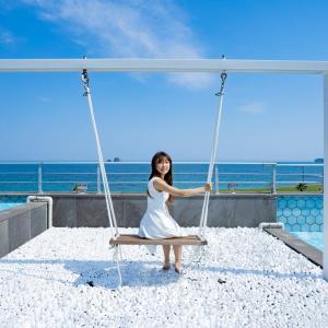 a woman sitting on a swing at the beach at Sun and Moon Resort in Seogwipo