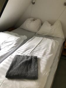 ein weißes Bett mit einem schwarzen Handtuch drauf in der Unterkunft vakantiehuisje Gerolstein in Gerolstein