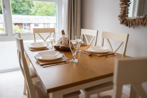 a wooden table with plates and glasses on it at Stylish Brixham Apartment - Free on street parking in Brixham