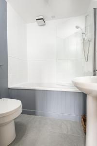 a white bathroom with a toilet and a sink at Madeira In Fife in Pittenweem