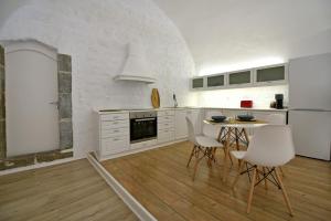 a kitchen with white cabinets and a table and chairs at Hydra Hospitality Port Apartment in Hydra