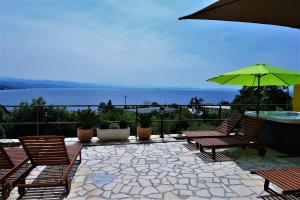 a patio with chairs and a table and an umbrella at Apartments and Rooms Vila Irma in Opatija