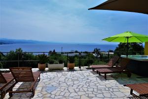 un patio con sillas, una mesa y una sombrilla en Apartments and Rooms Vila Irma, en Opatija