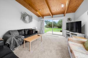 a living room with a couch and a tv at Stroll to the Sea - Te Horo Beach Holiday House in Te Horo