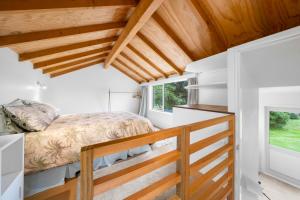 a bedroom in a tiny house with a bed and a window at Stroll to the Sea - Te Horo Beach Holiday House in Te Horo