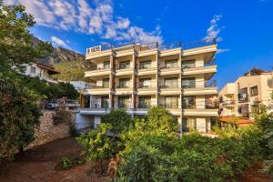 a tall white building with trees in front of it at Neva Kaş in Kaş