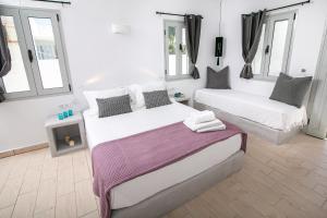 two beds in a room with white walls and windows at Sensia Luxury Apartment with Hot tub in Oia