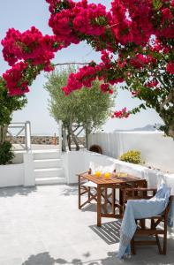 una mesa y sillas bajo un árbol con flores rosas en Sensia Luxury Apartment with Hot tub, en Oia