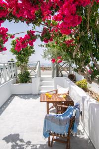 a table and chairs on a patio with pink flowers at Sensia Luxury Apartment with Hot tub in Oia