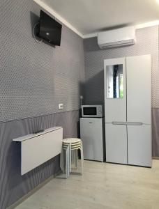 a kitchen with a refrigerator and a table and a stool at Santorini Odesa in Odesa