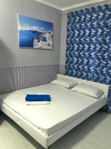 a bed in a room with a blue and white curtain at Santorini Odesa in Odesa