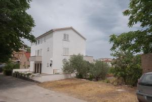 ein weißes Haus auf einer Straße mit Bäumen in der Unterkunft Apartments Dilk in Vis
