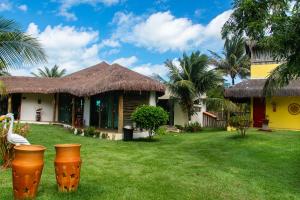 uma casa com um quintal gramado com dois vasos grandes em POUSADA PONTA DA ASA em Coruripe