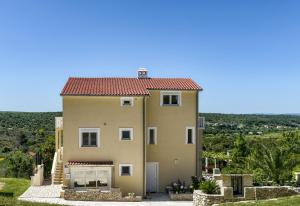 une grande maison bien exposée avec un toit rouge dans l'établissement Haus Lilli mit Pool, à Ražanac