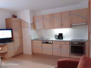 eine Küche mit Holzschränken und einem TV in der Unterkunft Apartment in Fügenberg/Zillertal 727 in Pankrazberg