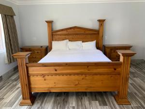 a bedroom with a wooden bed with white sheets at Viking Motel-Ventura in Ventura