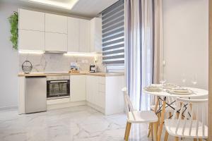 een keuken met witte kasten en een tafel en stoelen bij Elegant Central Apartment Veria - με ενδοδαπέδια θέρμανση!!! in Veria