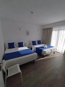 2 Betten in einem Zimmer mit blauen Kissen in der Unterkunft Residencial Tropicália AL in Praia da Barra