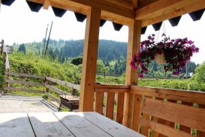 a porch of a wooden cabin with a bench and flowers at Затишний котедж "Хатинка" in Yablunytsya +25 photos