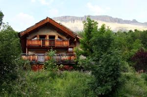 a log cabin with a balcony in the trees at La Paille in Pelvoux