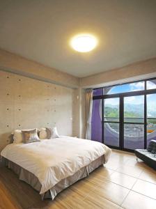 een slaapkamer met een groot bed en een groot raam bij Mei Jen house B&B 日月潭民宿 in Yuchi