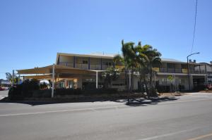 a building with a palm tree in front of a street at The Australian Hotel Motel in Dalby
